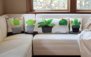Finished cactus accent pillows made from the Cactus Applique Pillows Sewing Pattern by Jennifer Jangles, displayed on a couch 