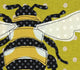 Detail view of the Bee Applique Hoop Art Sewing Pattern by Jennifer Jangles sewn onto a green with white polka dot fabric